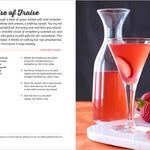 Page out of a book. Strawberry-themed cocktail with a glass and carafe on a table, accompanied by strawberries.
