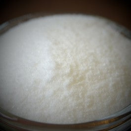 A close-up of a glass bowl filled with white powder on a dark background