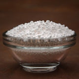 Glass bowl filled with white beads on a brown background