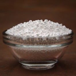 Glass bowl filled with white beads on a brown background