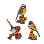 Three colorful bird figurines on branches with flowers against a white background