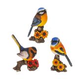 Three colorful bird figurines on branches with flowers against a white background