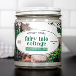 Candle jar labeled 'fairy tale cottage' with a scenic design on the label.