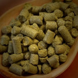 Greene hops pellets in a wooden bowl on a dark background
