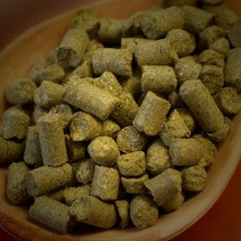 Greene hops pellets in a wooden bowl on a dark background