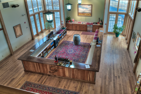 Large room with wooden floor, high windows, and a central wooden tasting counter that wraps around the inside of the room.