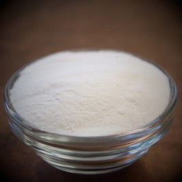 Glass bowl filled with white powder on a dark background