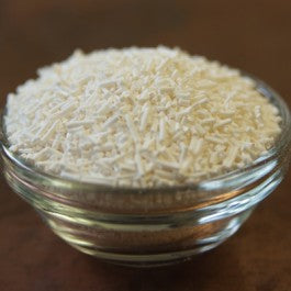 Glass jar filled with small white pellets on a wooden surface