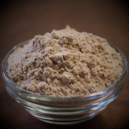 Glass bowl filled with brown powder on a dark background