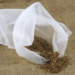 White mesh bag with dried herbs on a textured brown surface