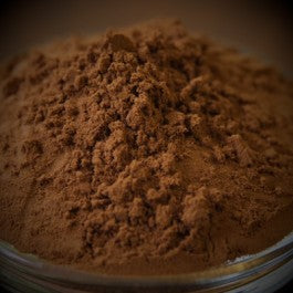Close-up of brown powder in a glass container with a blurred background