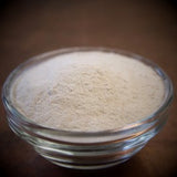 Glass bowl filled with a white powdery substance on a dark background