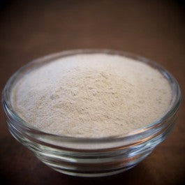 Glass bowl filled with a white powdery substance on a dark background