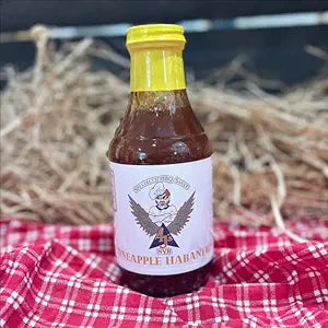 barbecue sauce bottle on a red picnic table cloth with a straw hay background