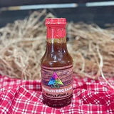 barbecue sauce bottle on red table cloth with a straw hay background
