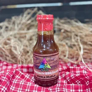 barbecue sauce bottle on red table cloth with a straw hay background