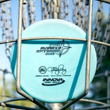 Disc golf disc with branding on a disc golf basket