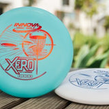 Two disc golf discs on a wooden surface with a blurred outdoor background