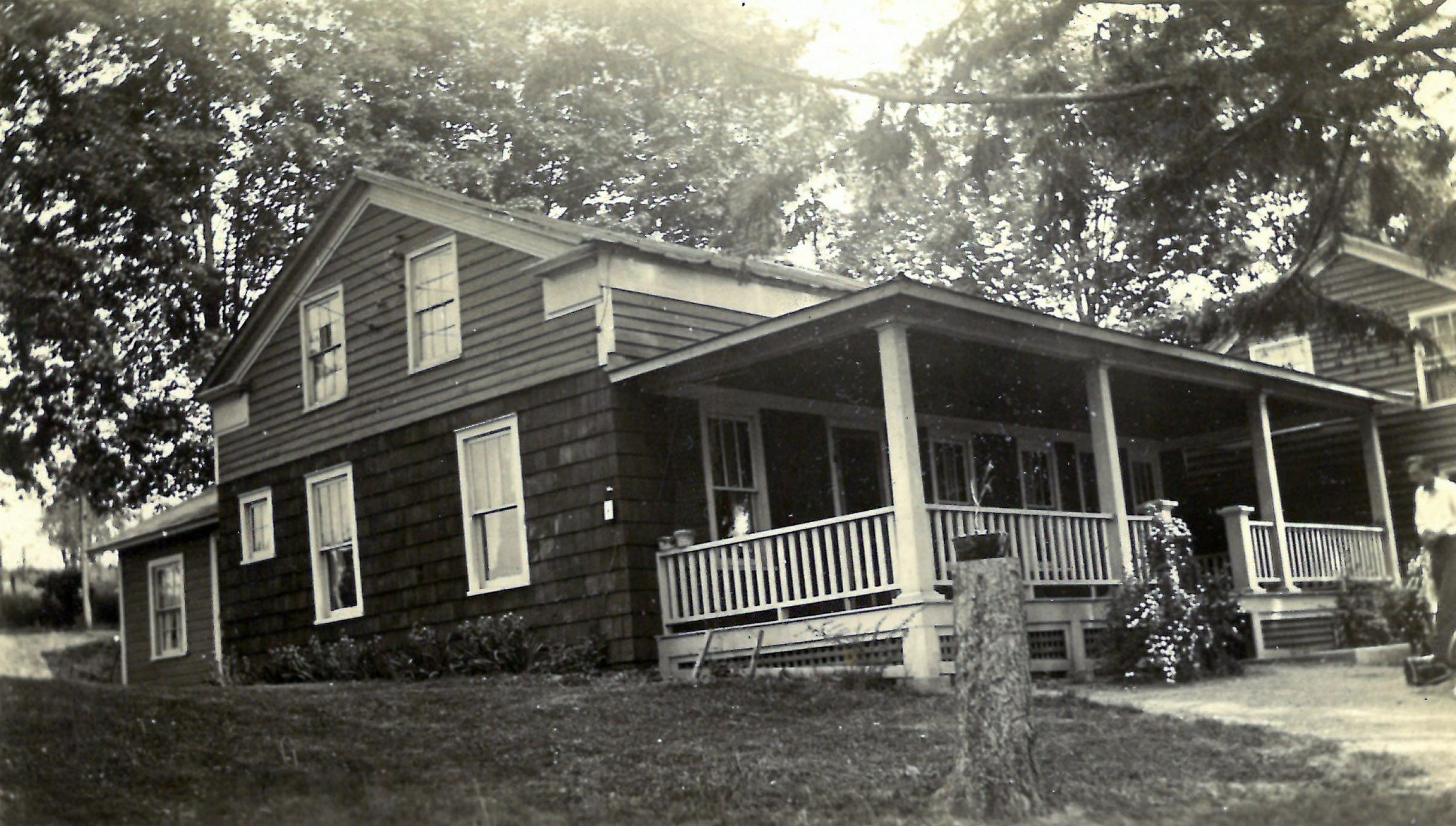 Vintage black and white photo of a two-story house with a porch