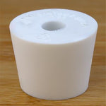 White rubber bottle stopper with hole on a wooden background