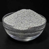 Glass bowl filled with gray clay powder on a black background