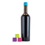Dark glass bottle with a blue cap and three colorful silicone bottle caps on a white background