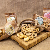 Dried breadsticks on a wooden board with branded bags in the background.