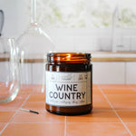 Candle labeled 'Wine Country' on a tiled surface with a blurred background