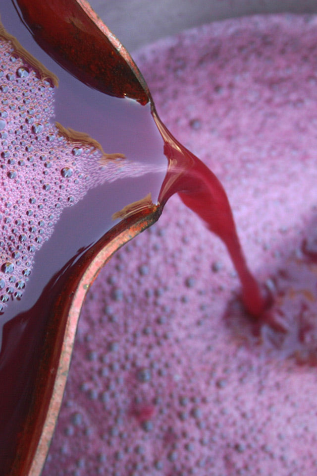 Close-up of red liquid being pressed onto a container